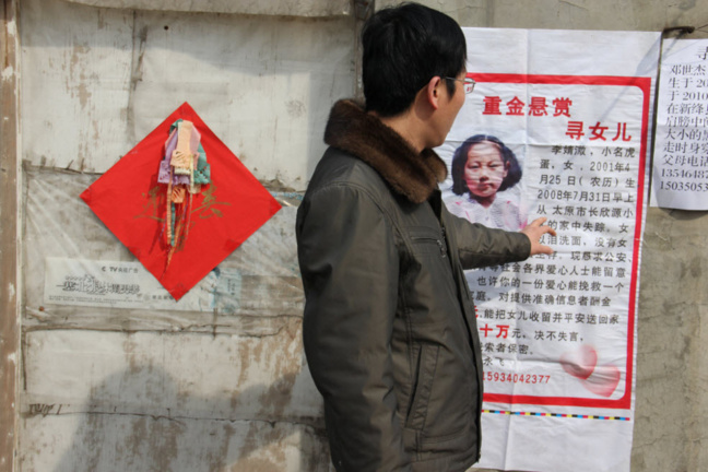 Un homme devant le poster signalant le rapt d'un enfant